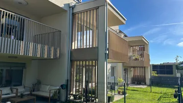 Moderne Wohnanlage mit Balkonen, einer möblierten Terrasse und gepflegtem Rasenbereich.