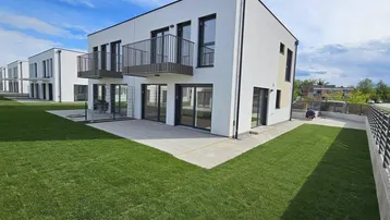 Reihe moderner Häuser mit gepflegten Gärten und Terrassen unter einem weiten Himmel.