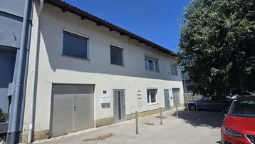 Vorderansicht eines Mehrfamilienhauses mit Garagentor und Eingangsbereichen unter blauem Himmel.
