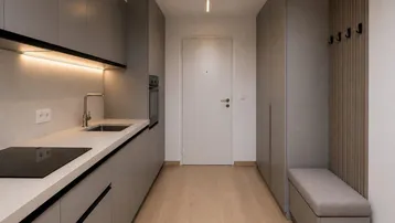 Moderne Küchenzeile mit grauen Fronten und integriertem Kochfeld, kombiniert mit einem Eingangsbereich.
