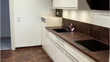 Moderne Küche mit weißen Schränken, dunkler Arbeitsplatte und gemusterten Fliesenboden.