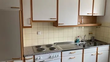 Funktionale Küche mit weißen Schränken, Granitarbeitsplatte und integriertem Herd.