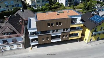 Modernes Mehrfamilienhaus mit Holzfassade und gelben Akzenten in einer Wohngegend.