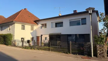 Ansicht von zwei Wohnhäusern von der Straße aus mit unterschiedlichen Baustilen und Dächern.
