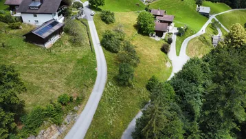 Luftaufnahme einer ländlichen Gegend mit Häusern, Straßen und grünen Hügeln.