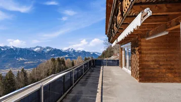 Große Terrasse mit Holzboden und atemberaubendem Bergblick, ideal für Entspannung im Freien.