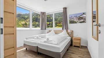 Helles Schlafzimmer mit großen Fenstern und malerischem Bergblick.
