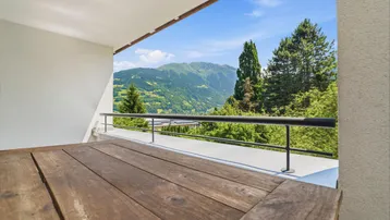 Balkon mit Panoramablick auf die umliegenden Berge und grüne Täler.