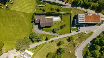 Vogelperspektive des Anwesens mit Haus, Pool und angrenzendem Gebäude mit Solaranlage.