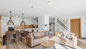 Heller offener Wohn- und Essbereich mit integrierter Küche und gemütlichem Sofa.