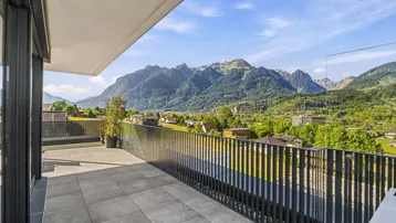 Große Terrasse mit Fliesenboden und atemberaubendem Bergblick unter blauem Himmel.