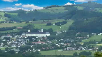 Panoramablick auf eine malerische Stadt mit einem historischen Gebäude inmitten grüner Hügel.