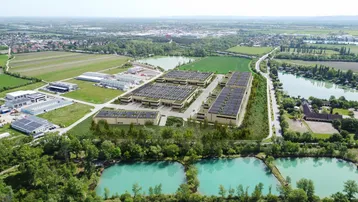Luftaufnahme eines großen Gewerbekomplexes mit mehreren Gebäuden, umgeben von grünen Feldern und Gewässern. Solarpaneele sind auf den Dächern sichtbar.