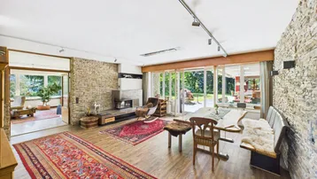 Geräumiger Wohn-Essbereich mit Steinwand, Kamin und Zugang zur Terrasse.