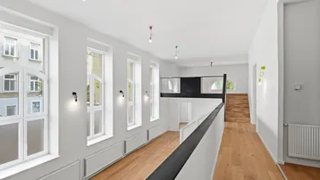 Heller, offener Wohnbereich mit hohen Decken, Holzfußboden und einer Galerieebene.