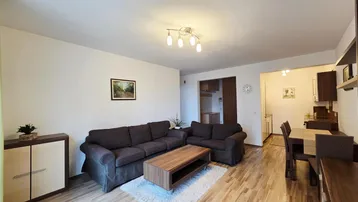 Gemütlicher Wohn- und Essbereich mit bequemen Sofas, Holzboden und einem Esstisch im Hintergrund.