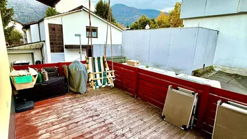 Geräumige Terrasse mit Schaukel und Blick auf die umliegende Landschaft und Berge.