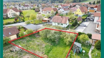 Luftaufnahme eines Baugrundstücks mit roter Umrandung in ländlicher Umgebung.