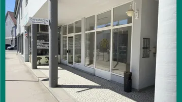 Helle Geschäftsfassade mit großen Schaufenstern und modernem Design, gut beleuchtet von der Sonne.