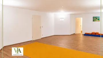 Geräumiger Mehrzweckraum mit hellem Laminatboden und weißen Wänden, ideal für verschiedene Aktivitäten.