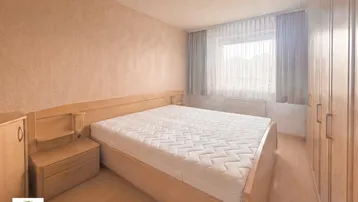 Helles Schlafzimmer mit Holzbett, Nachttisch und großem Kleiderschrank, bietet eine gemütliche Atmosphäre.