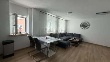 Heller Wohn- und Essbereich mit modernem Sofa, Esstisch und Holzfußboden, ideal für geselliges Beisammensein.