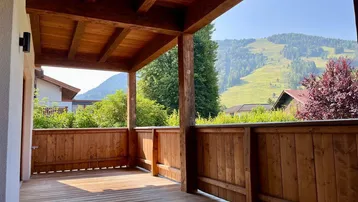 Geräumige Holzterrasse mit Bergblick und viel Grün, ideal zum Entspannen im Freien.