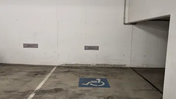 Tiefgaragenstellplatz mit markiertem Behindertenparkplatz und robustem Betonboden.