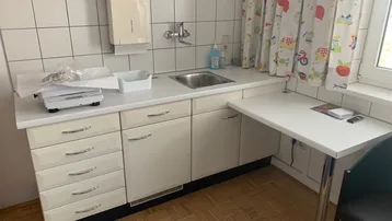 Kleine Küchenzeile mit Spülbecken, Arbeitsfläche und Klapptisch, ideal für eine Praxis oder ein Büro.