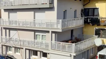 Mehrfamilienhaus mit mehreren Balkonen und Garagenzufahrt in sonniger Lage.