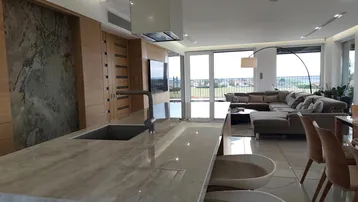 Moderne offene Küche mit Kochinsel, Essbereich und Wohnzimmer mit Zugang zur Terrasse.