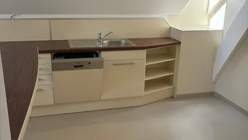Helle Küchenzeile im Dachgeschoss mit Einbaugeschirrspüler und Dachfenster für natürliches Licht.