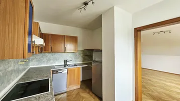 Küche im Dachgeschoss mit Holzschränken, Granitarbeitsplatte und Parkettboden, offen zu einem weiteren Raum.