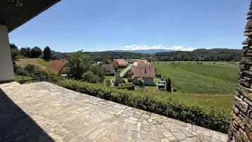Große gepflasterte Terrasse mit weitem Blick über Felder und die umliegende Landschaft.