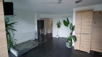 Gemütlicher Wohnbereich mit Kaminofen, dunklen Fliesen und modernen Holzschränken.