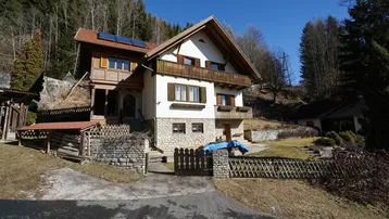 Traditionelles Haus in den Bergen mit Balkonen und Photovoltaikanlage auf dem Dach.