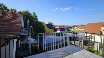 Geräumige Dachterrasse mit Fliesenboden und weitem Blick über die umliegende Wohnsiedlung.