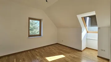 Helles Schlafzimmer mit Parkettboden, Dachschräge und zwei Fenstern für viel Tageslicht.