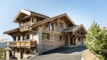 Großzügiges Holzchalet mit traditioneller Architektur und mehreren Balkonen in alpiner Umgebung.