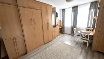 Helles Wohnzimmer mit integriertem Schrankbett, Esstisch und Laminatboden.