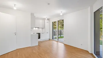 Heller offener Wohn- und Essbereich mit integrierter Küche und Zugang zur Terrasse.