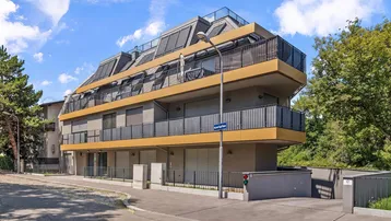 Modernes Mehrfamilienhaus mit markanter Architektur, Balkonen und Dachterrassen.