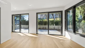 Helles Wohnzimmer mit Holzboden und großen Schiebetüren zur Terrasse.