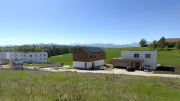 Panoramablick auf moderne Häuser und Wohngebäude in ländlicher Umgebung mit Bergsicht.