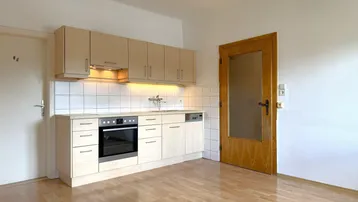 Kleine Einbauküche mit hellen Holzfronten, Fliesenrückwand und integrierten Geräten.