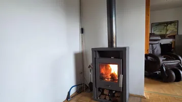 Gemütliches Wohnzimmer mit modernem Holzofen und Parkettboden für warme Abende.