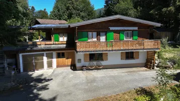 Charmantes Holzhaus mit traditionellen grünen Fensterläden und einem Balkon in ländlicher Umgebung.