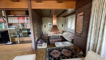 Wohnzimmer mit rustikalem Kamin, Ziegelwänden und Holzbalkendecke.