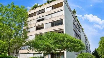 Mehrstöckiges Wohngebäude mit begrüntem Flachdach, vielen Fenstern und moderner Architektur.