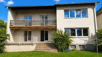 Fassade eines Einfamilienhauses mit Balkon, Terrasse und großem Gartenbereich.
